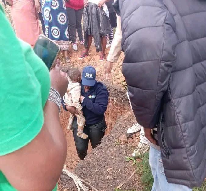 Law enforcement officer carrying missing boy Nkosingiphile Ntiwane out of the pit where he was found in Masoyi, Mpumalanga