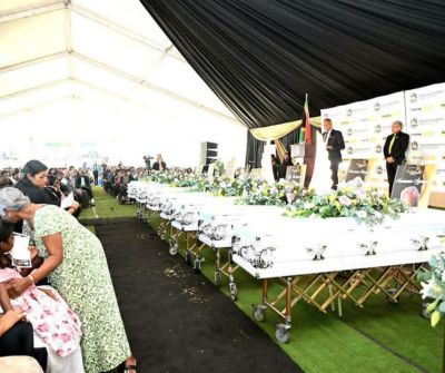 Thamsanqa Ntuli speaking in front of coffins at Monswamy family funeral